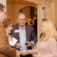 Four reception guests greeting each other, two of them shaking hands